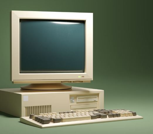A beige 1990s desktop computer, monitor and keyboard on a green background